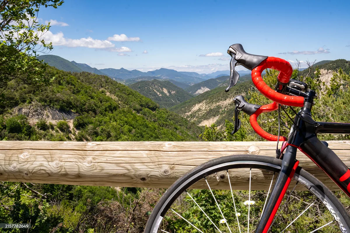 Cycliste sur route panoramique, vue dégagée au loin.